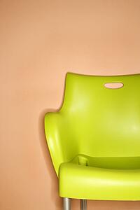 Green plastic chair against orange wall