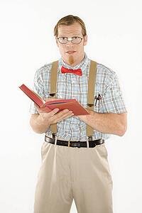 Young man dressed like nerd with book open, looking at viewer