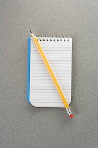 Pencil on top of open spiral bound notepad