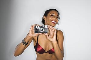 Woman in bra holding up camera smiling