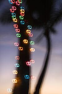 Colored lights on palm tree abstracted by camera movement