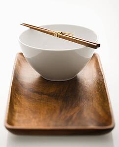 Asian bowl with chopsticks on wooden tray