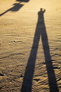 Shadow of man on dirt at sundown