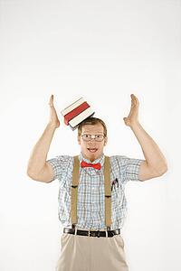Young man dressed like nerd with books sliding off head