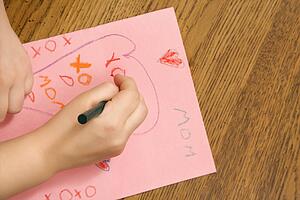 Child hands drawing on paper with crayons