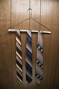Three retro ties hanging on a wire hanger against wood paneling