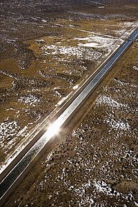 Aerial landscape of water canal running though rural Colorado with sun reflection