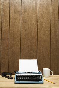 Vintage typewriter, coffee cup, pencil and stapler on desk