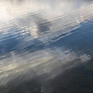 Reflections of cloud formations on rippling water