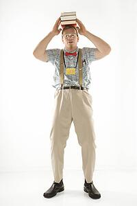 Young man dressed like nerd balancing books on head looking at viewer