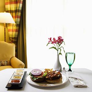 Room service cheeseburger meal with flowers and condiments