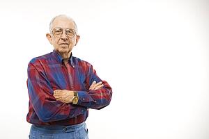 Portrait of an elderly man wearing plaid shirt with arms crossed