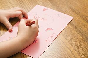 Child hands drawing on paper with crayons