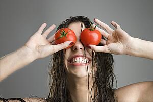 Woman with tomatoes covering her eyes
