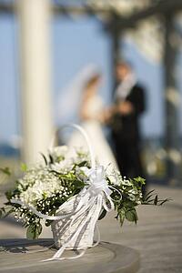 Flower basket with bride and groom blurred in background