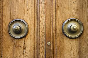 Brass doorknobs on wooden door with lock.