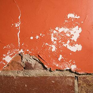 Red wall with cracking plaster and brick