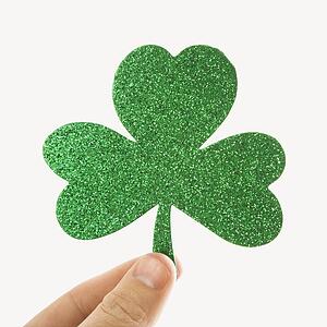 Hand holding a green glitter paper shamrock