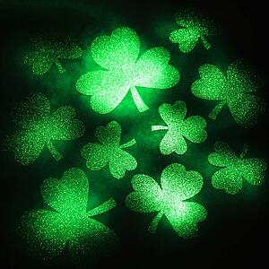 Group of green shamrocks reflecting light on black background