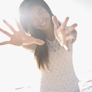 Young woman with arms and hands stretched out toward viewer.