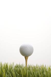 Studio shot of golf ball resting on tee in grass