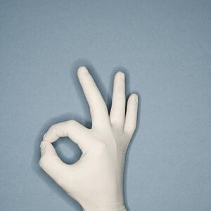 Hand wearing white rubber glove making a gesture meaning okay