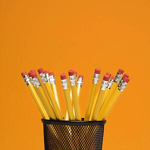 Group of pencils in pencil holder on orange background