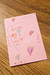 Child drawing with crayons on pink paper