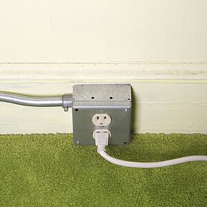 Close-up of silver wall outlet with plug inserted