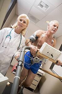 Doctor Monitoring The Heart-Rate Of Patient On A Treadmill