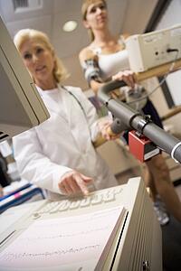 Doctor Monitoring The Heart-Rate Of Patient On A Treadmill