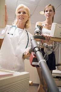 Doctor Monitoring The Heart-Rate Of Patient On A Treadmill