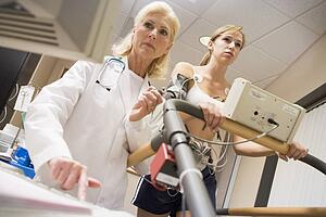 Doctor Monitoring The Heart-Rate Of Patient On A Treadmill