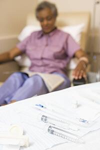 Syringes On A Table With A Patient In The Background
