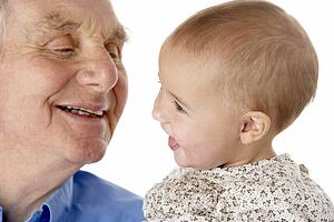 Portrait of grandfather and granddaughter, smiling at each other