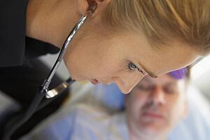 Paramedic using stethoscope on patient in ambulance