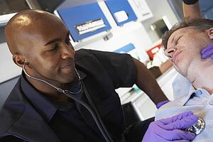 Paramedic listening to patients heartbeat
