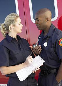Two paramedics having a serious discussion, with ambulance in background