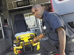Paramedic removing empty gurney from ambulance
