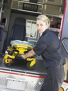 Paramedic removing empty gurney from ambulance