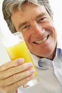 Senior Man Smiling At Camera And Drinking Orange Juice