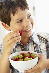 Young Boy Eating Bowl Of Fresh Fruit