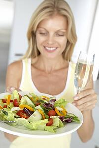 Mid Adult Woman Holding A Wine Glass And Fresh Salad