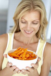 Mid Adult Woman Holding A Bowl Of Carrots