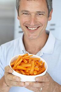 Middle Aged Man Holding A Bowl Of Carrots