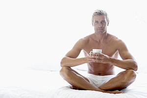 Mid Adult Man Sitting On Bed And Drinking Coffee