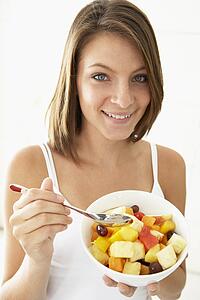Young Woman Eating Fresh Fruit Salad