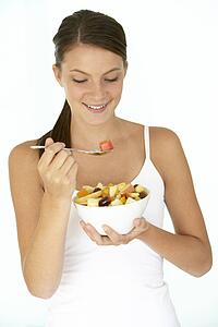 Young Woman Eating Fresh Fruit Salad
