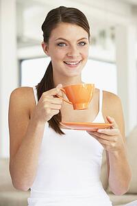 Young Woman Drinking Out Of An Orange Cup