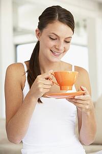 Young Woman Drinking Out Of An Orange Cup